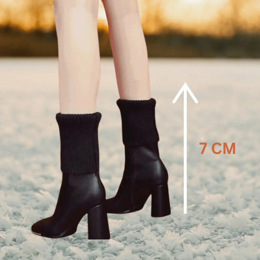 Woman wearing black heeled ankle boots with thick socks, 7 cm heel, standing on snow