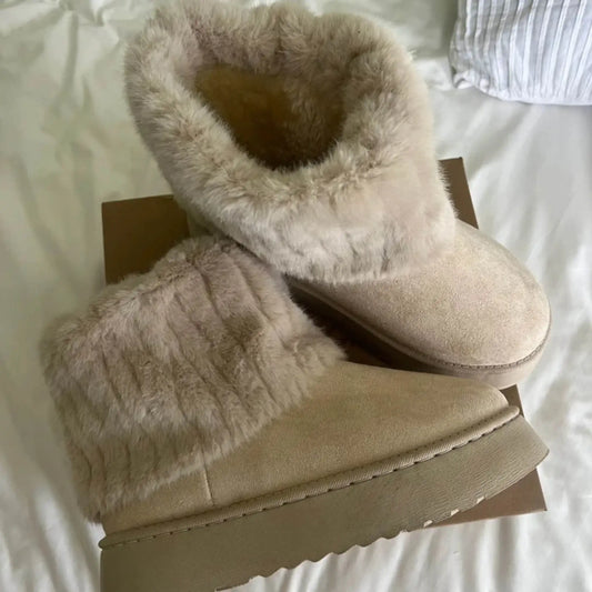 Beige faux fur ankle boots with thick soles on a box, cozy winter footwear