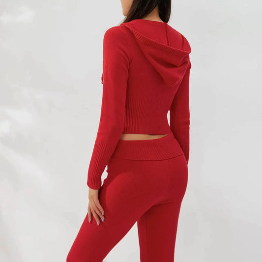 Woman wearing a fitted red knit hooded sweater and matching high-waisted pants set