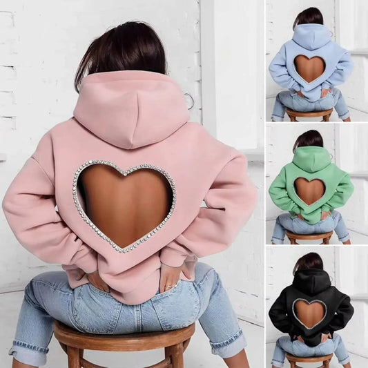 Trendy hoodie with rhinestone heart-shaped open back in pink, blue, green, and black, worn with jeans.