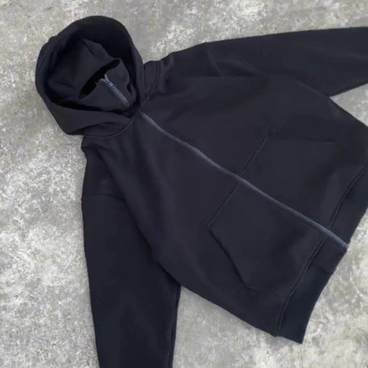 Black zip-up hoodie with front pockets laid flat on concrete surface