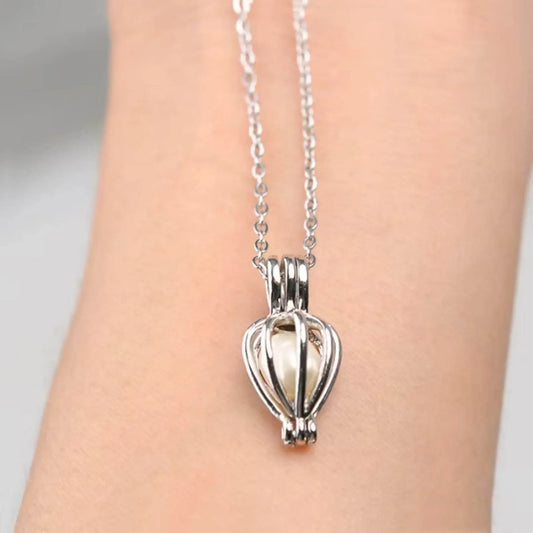 Silver chain necklace with a pearl caged pendant displayed on a person's wrist