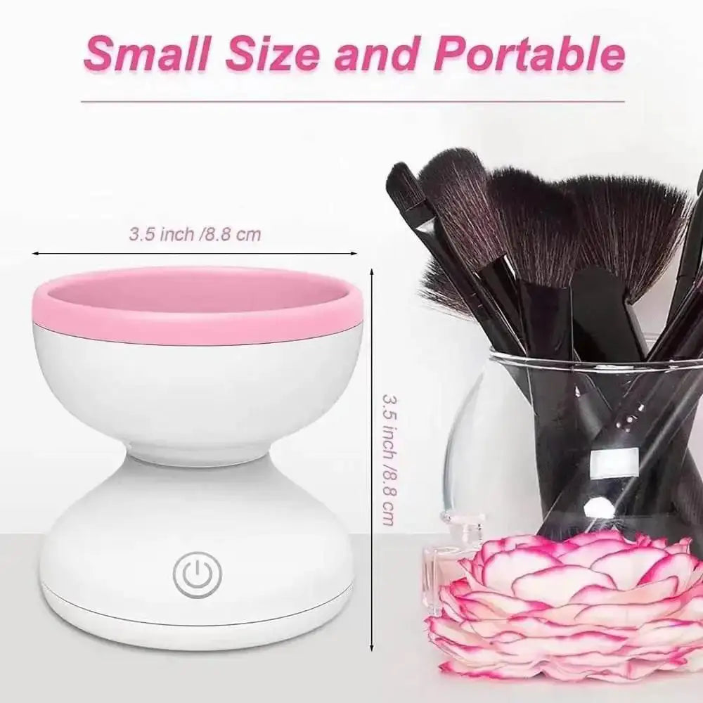 Small portable electric makeup brush cleaner with pink rim, makeup brushes in a glass cup nearby.