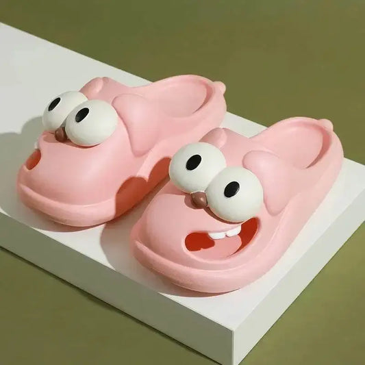 Pink cartoon character slippers with big eyes and playful face on a white platform