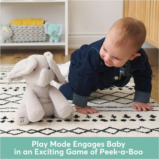 Baby playing on rug with plush elephant toy, nursery setting, peek-a-boo interactive toy