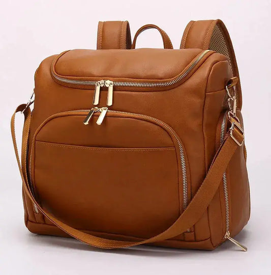 Tan leather backpack with gold zippers and multiple pockets, adjustable strap, on white background