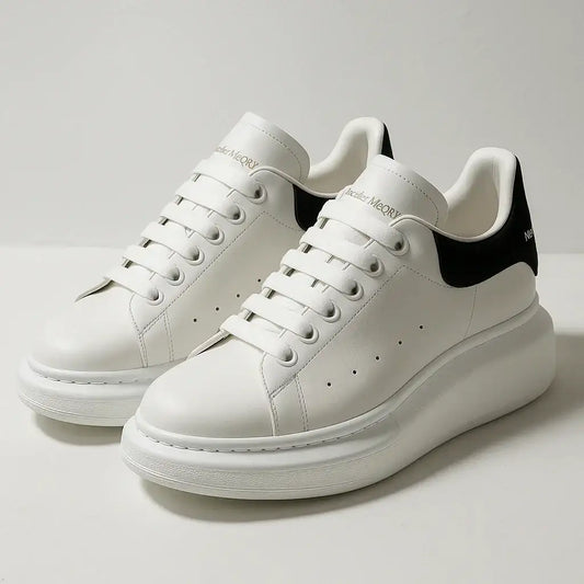 White platform sneakers with black heel detail, minimalist lace-up design on plain background.