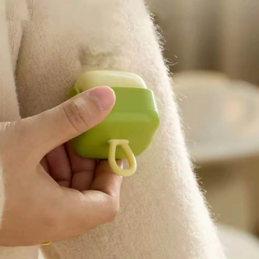 Hand using compact green fabric shaver to remove lint from a beige sweater