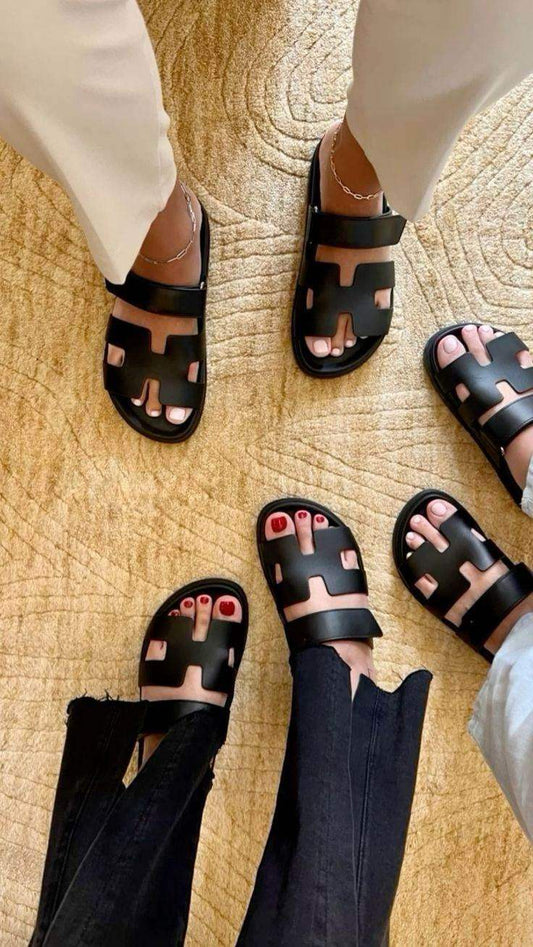 Group wearing black slip-on sandals with cutout design on beige textured rug