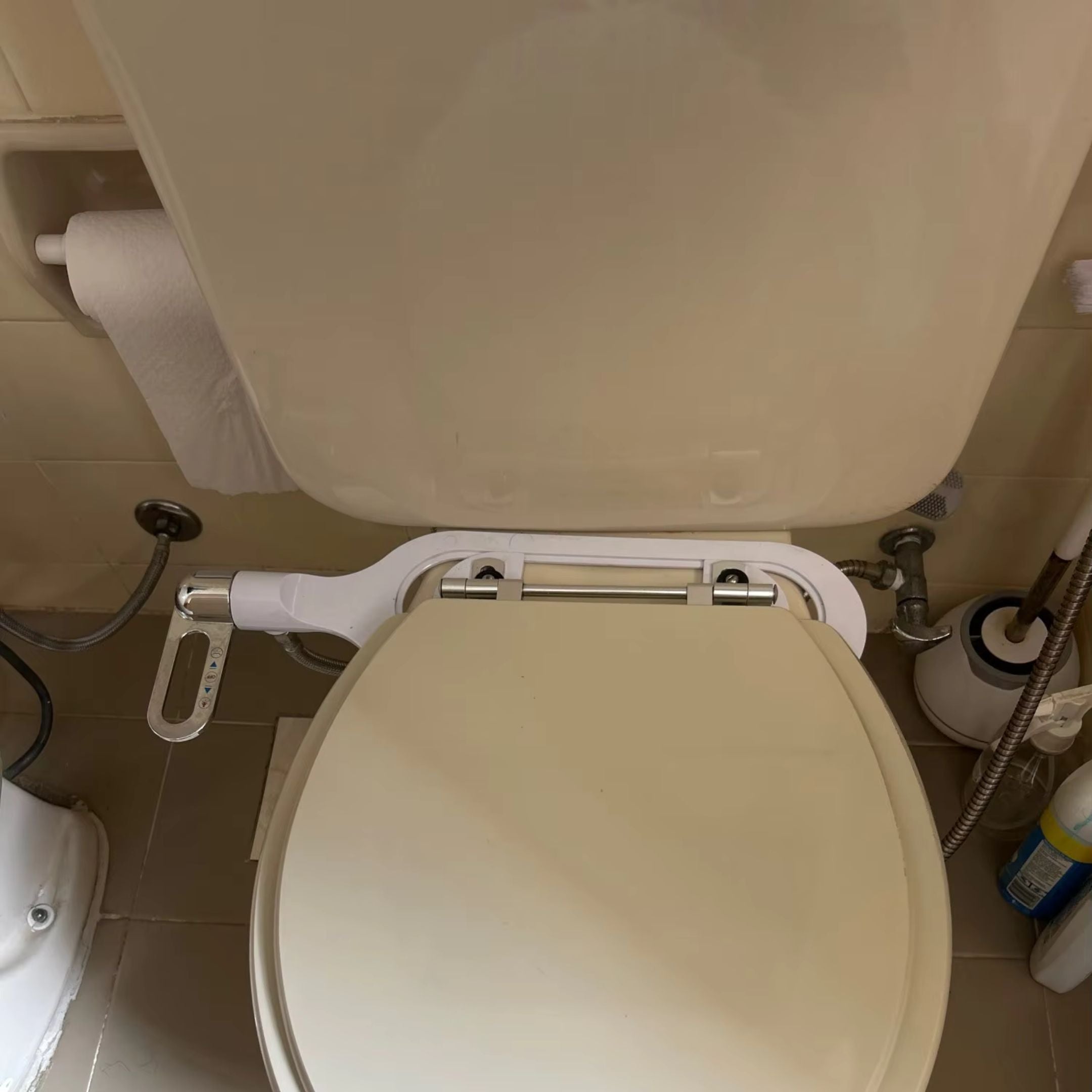 A bathroom with an open toilet and a visible toilet paper roll on the left.