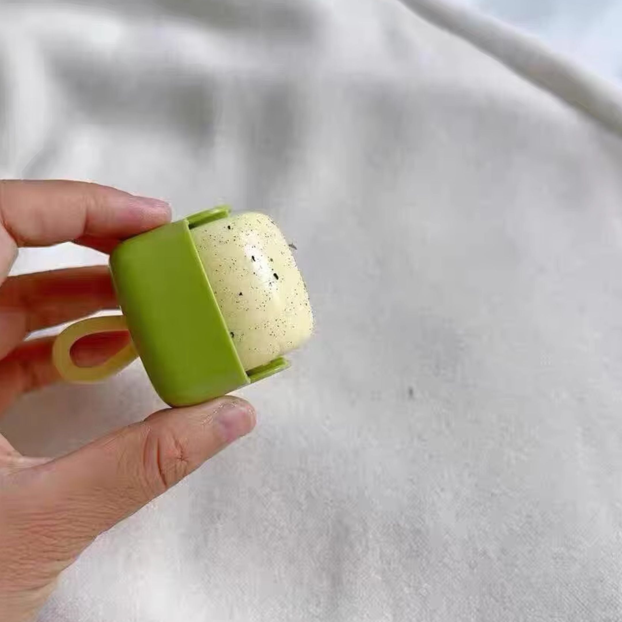 A person holds a small, black handheld gaming device connected to a large screen displaying a pixelated video game with bricks, sky, and a green hill. The game has text showing WORLD 1-1 and various numbers.